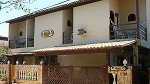 A two-story building with a balcony, a gated entrance, and potted plants. - Pousada Montreux (Mata de São João)
