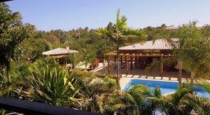 A pool area with a pergola and outdoor seating, surrounded by lush tropical vegetation. - VILLAGE IMBASSAI BREEZE (Mata de São João)