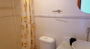 Un baño con inodoro, lavamanos y cortina de ducha.