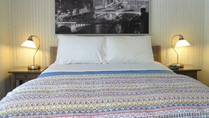 A hotel room with a bed, two bedside lamps, a large cityscape photograph on the wall, and a patterned bedspread. - The Saugatuck Retro Resort Motel (Saugatuck)