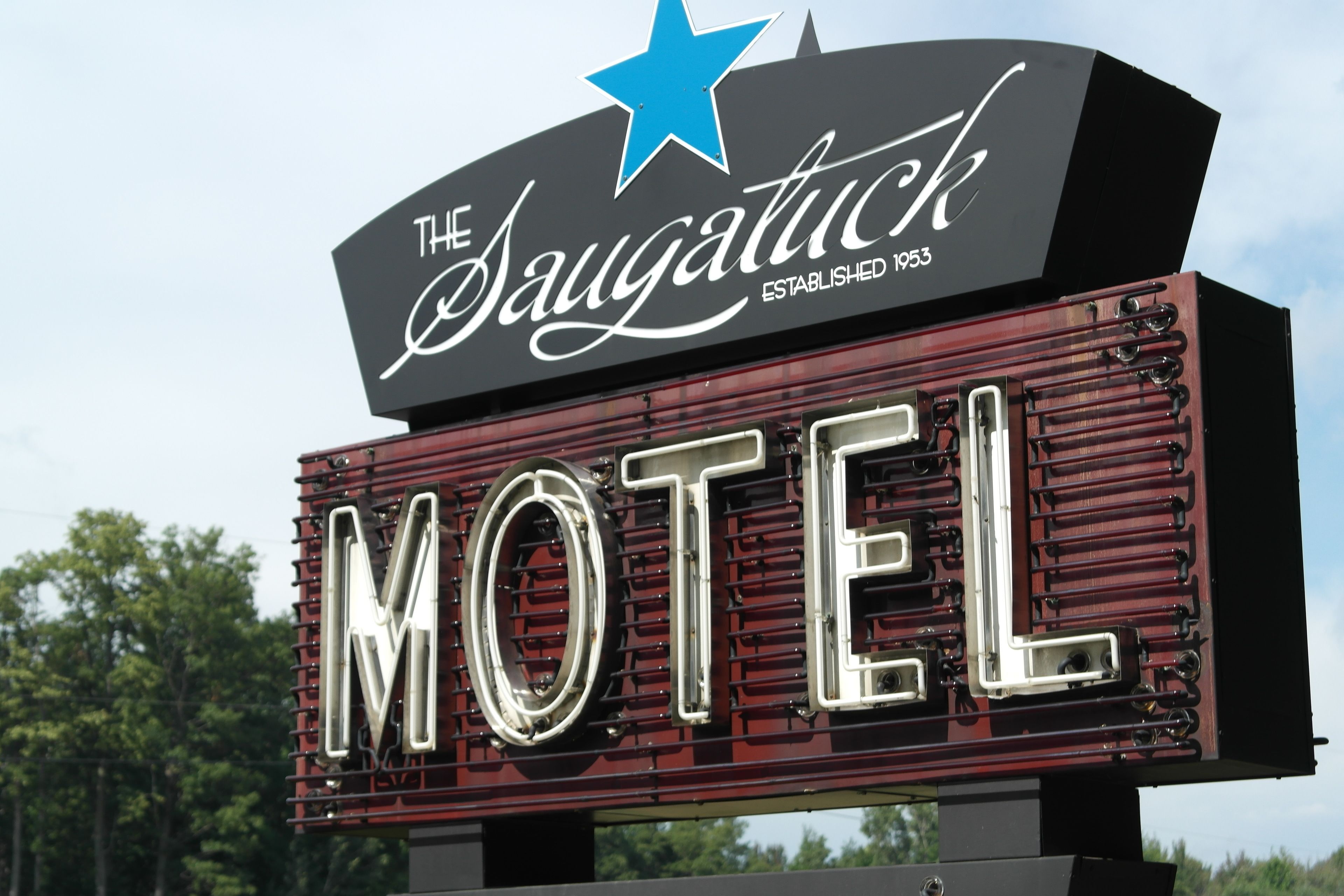 Une enseigne de motel avec les inscriptions « The Saugatuck » et « FONDÉ EN 1953 », et une grande enseigne « MOTEL » en dessous.