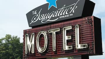 A motel sign with 'The Saugatuck' and 'ESTABLISHED 1953' text, and a large 'MOTEL' sign below.