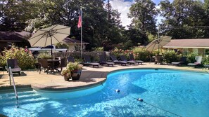 A swimming pool with lounge chairs and umbrellas, surrounded by trees and a stone wall. - The Saugatuck Retro Resort Motel (Saugatuck)