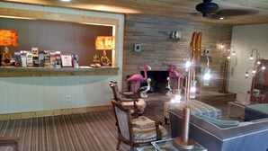 A bar area with a wooden counter, a seating area with patterned chairs, and a decorative flamingo statue. - The Saugatuck Retro Resort Motel (Saugatuck)
