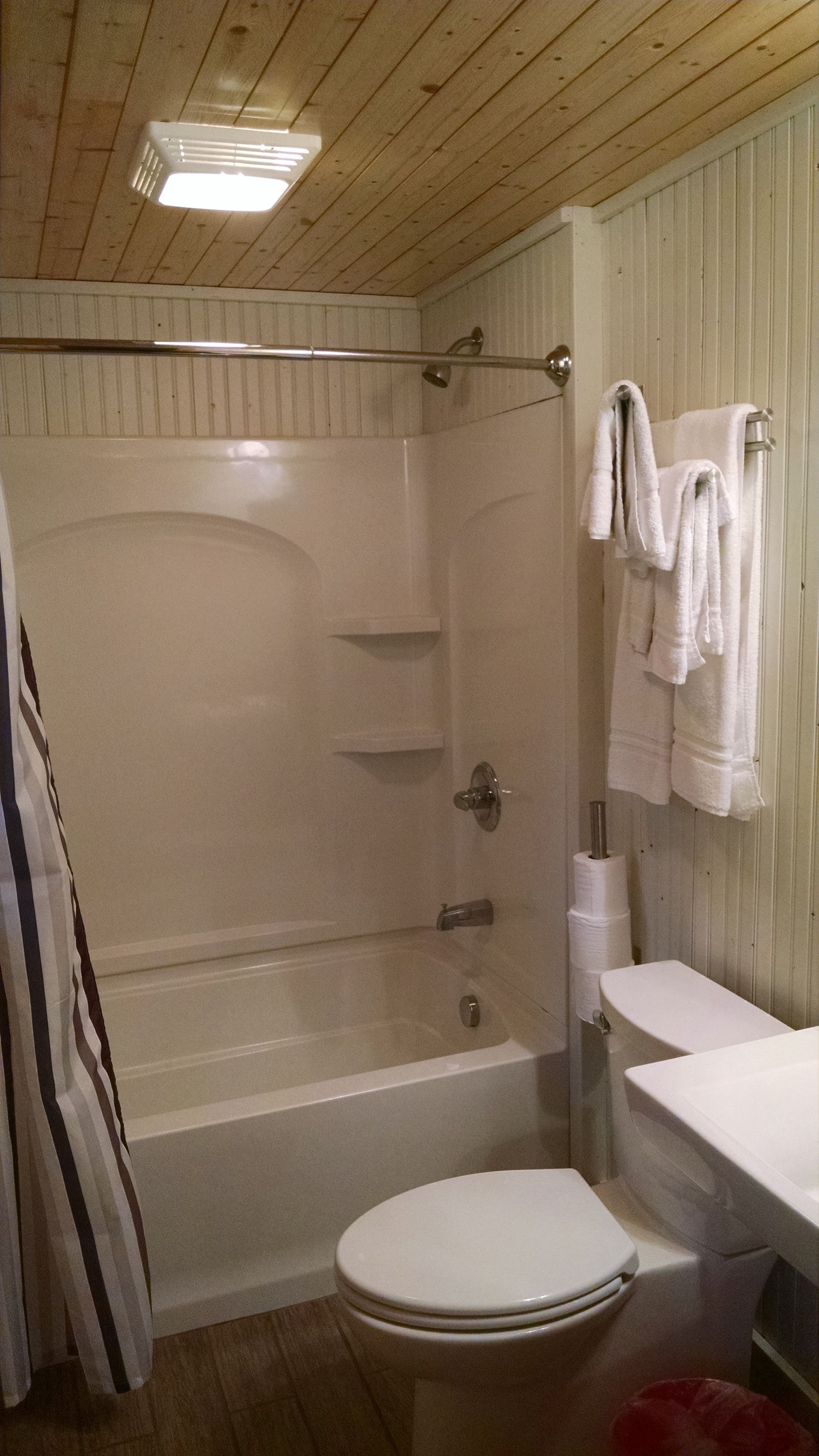 A bathroom with a shower, toilet, and a towel rack.