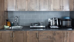 A kitchen with wooden cabinets, a stainless steel sink, a coffee maker, a microwave, and a portable stove. - Radium Chalet (Radium Hot Springs)