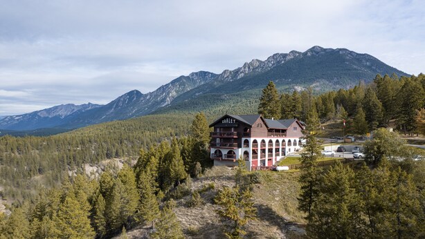A chalet with a balcony, surrounded by forest and mountains. - Radium Chalet (Radium Hot Springs)