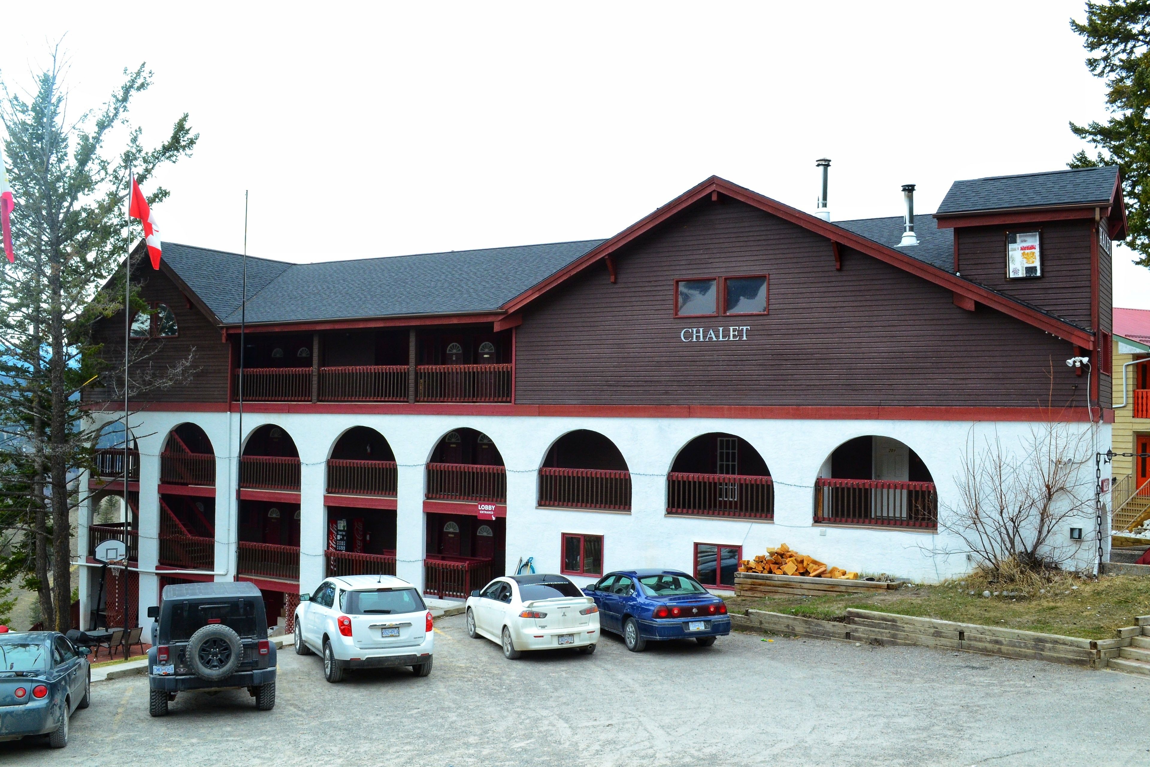 A building with a sign reading "CHALET" and a parking lot with several cars.