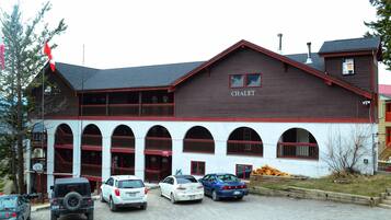 A building with a sign reading "CHALET" and a parking lot with several cars.