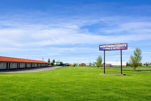 A motel with a sign reading "Northern Lights Inn & Suites" in a grassy area with a clear sky.