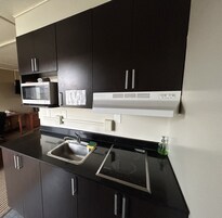 A modern kitchen with black cabinets, a microwave, a sink, and a stove.