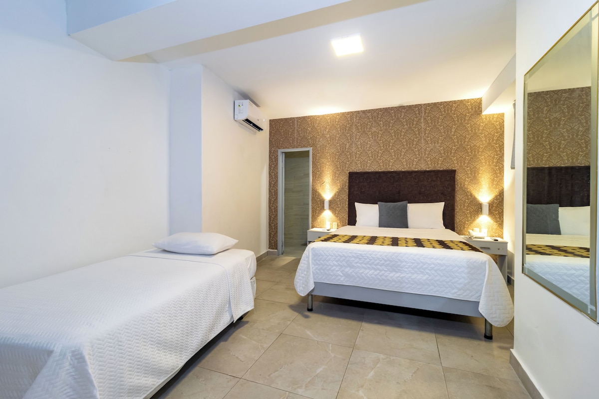 A hotel room with two beds, a large mirror, and a patterned wall.