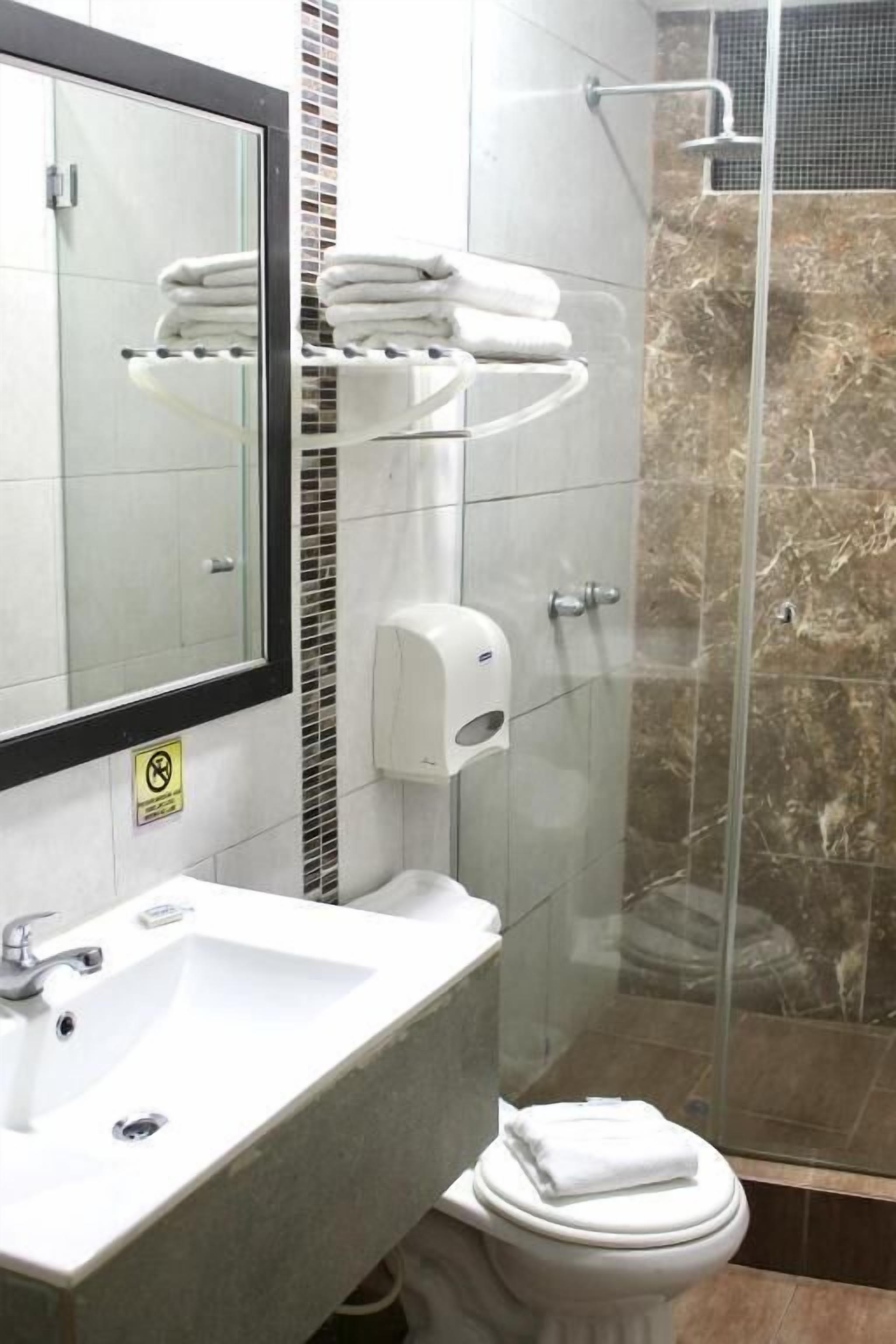 Baño con cabina de ducha de vidrio, lavamanos y retrete.