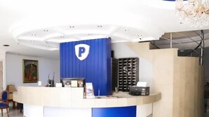 Een receptiebalie met een blauw-wit kleurenschema, een kroonluchter en een wandprinter.