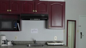 Cocina compacta con gabinetes rojo oscuro, un microondas, una cafetera y una estufa a gas.