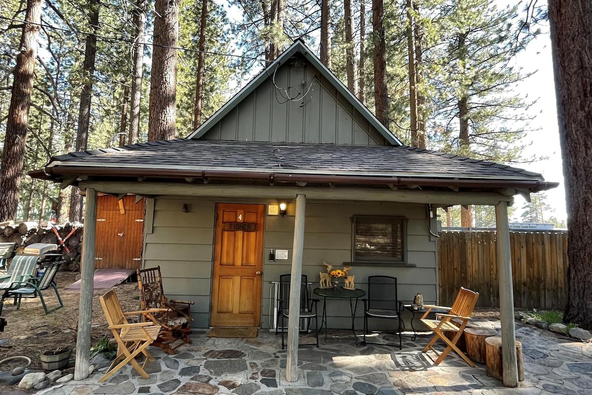 A cabin with a stone patio, wooden deck, and outdoor seating.