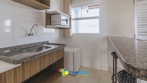 Eine moderne Küche mit einer Granitabdeckung, einer eingebauten Mikrowelle und einem kleinen Kühlschrank.