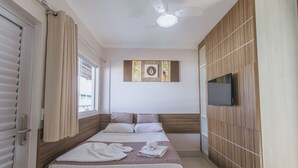 Ein Hotelzimmer mit zwei Betten, einem Flachbildfernseher, einem Deckenventilator und einem Fenster mit Vorhängen.