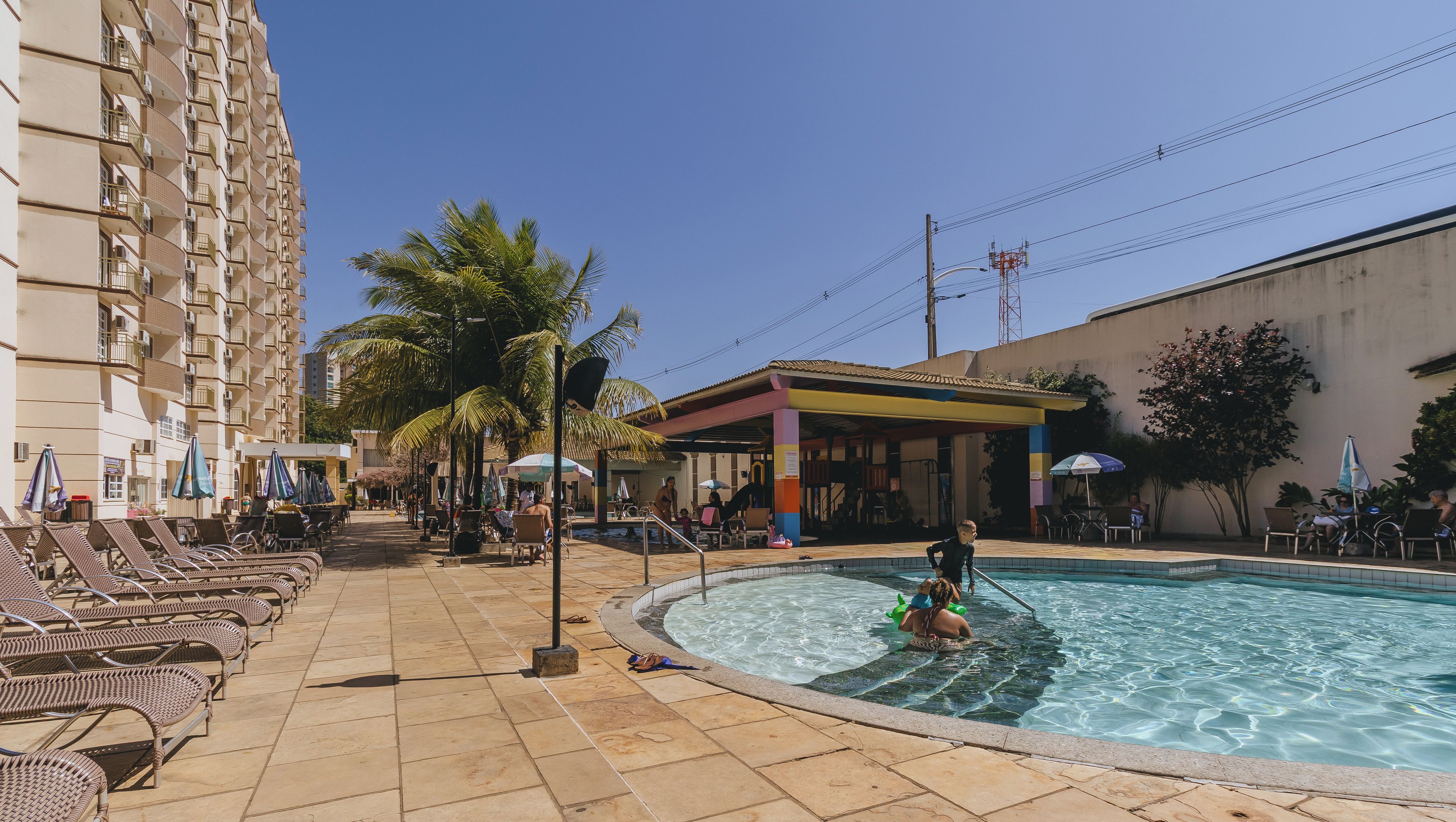 A pool area with lounge chairs, a small pool, and a building with balconies.