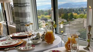 A table set for a meal with floral-patterned plates, a pitcher of orange juice, and a candle. - A Vista Villa Couples Retreat (Kelowna)