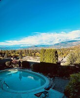 Una piscina con vistas a montañas y un paisaje urbano al fondo.