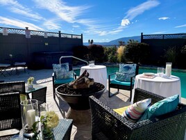 Un patio exterior con mobiliario de mimbre, un brasero y una piscina.