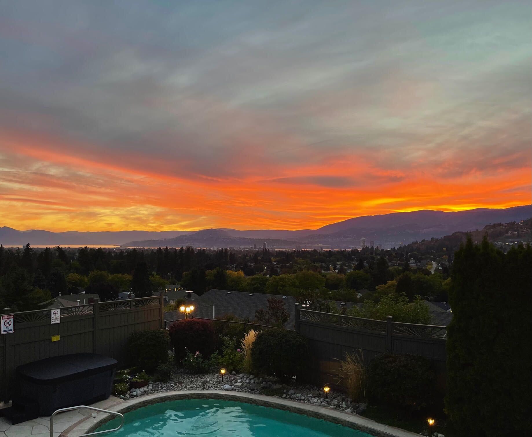 Piscina con vistas a montañas y un atardecer.