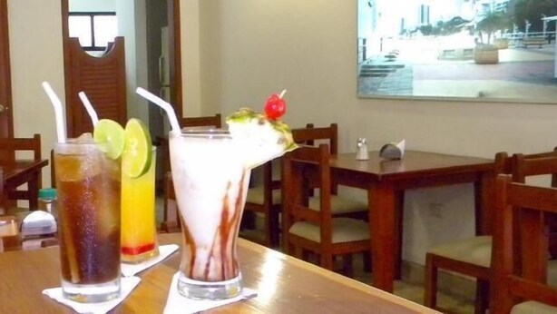 Una mesa con dos bebidas, una con pajita y rodajas de lima, y otra con cereza encima.
