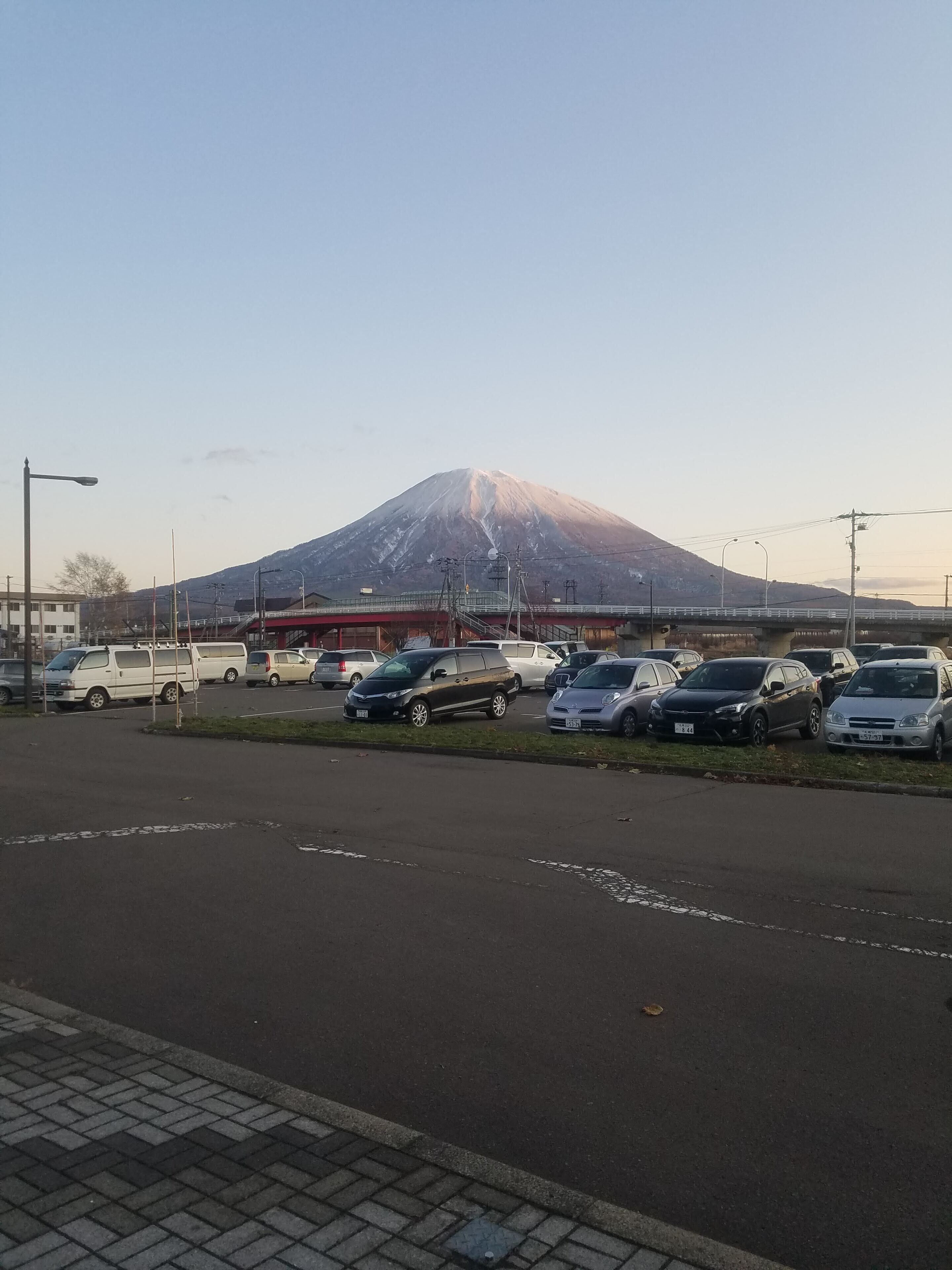 A parking lot with several cars and a bridge in the background.
