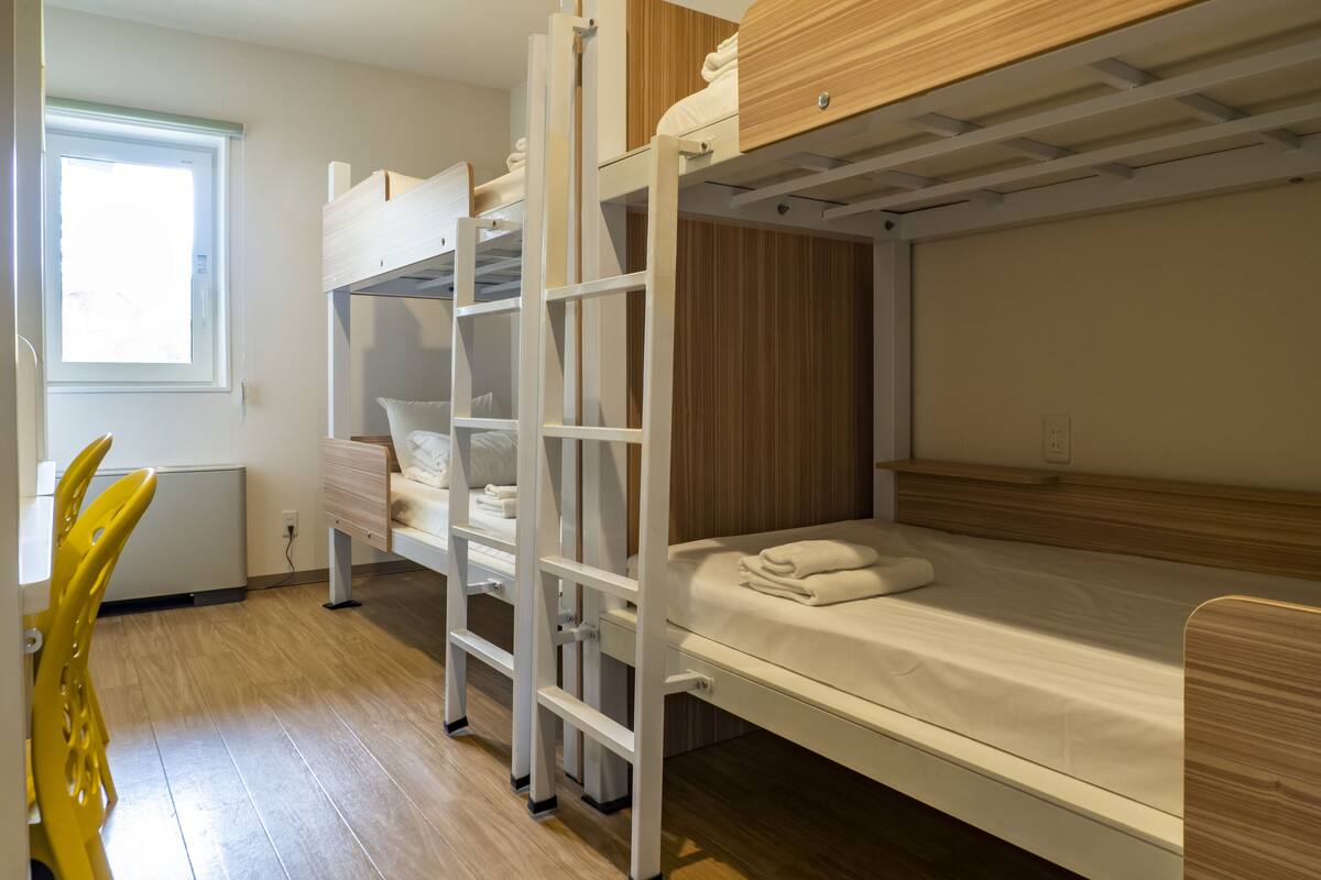 A bunk bed room with a wooden headboard, a white desk, and a chair.
