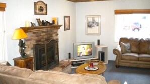 Un salon avec une cheminée en briques, un téléviseur, un canapé et une table basse.