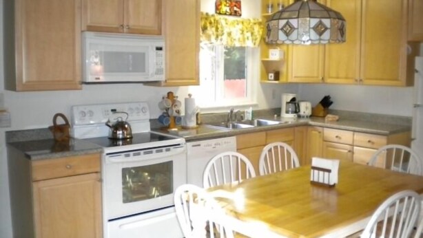 Une cuisine avec des meubles en bois, un four à micro-ondes, une cuisinière et une table à manger avec des chaises.