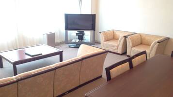 A living room with a flat-screen TV, a sofa, and a dining table.
