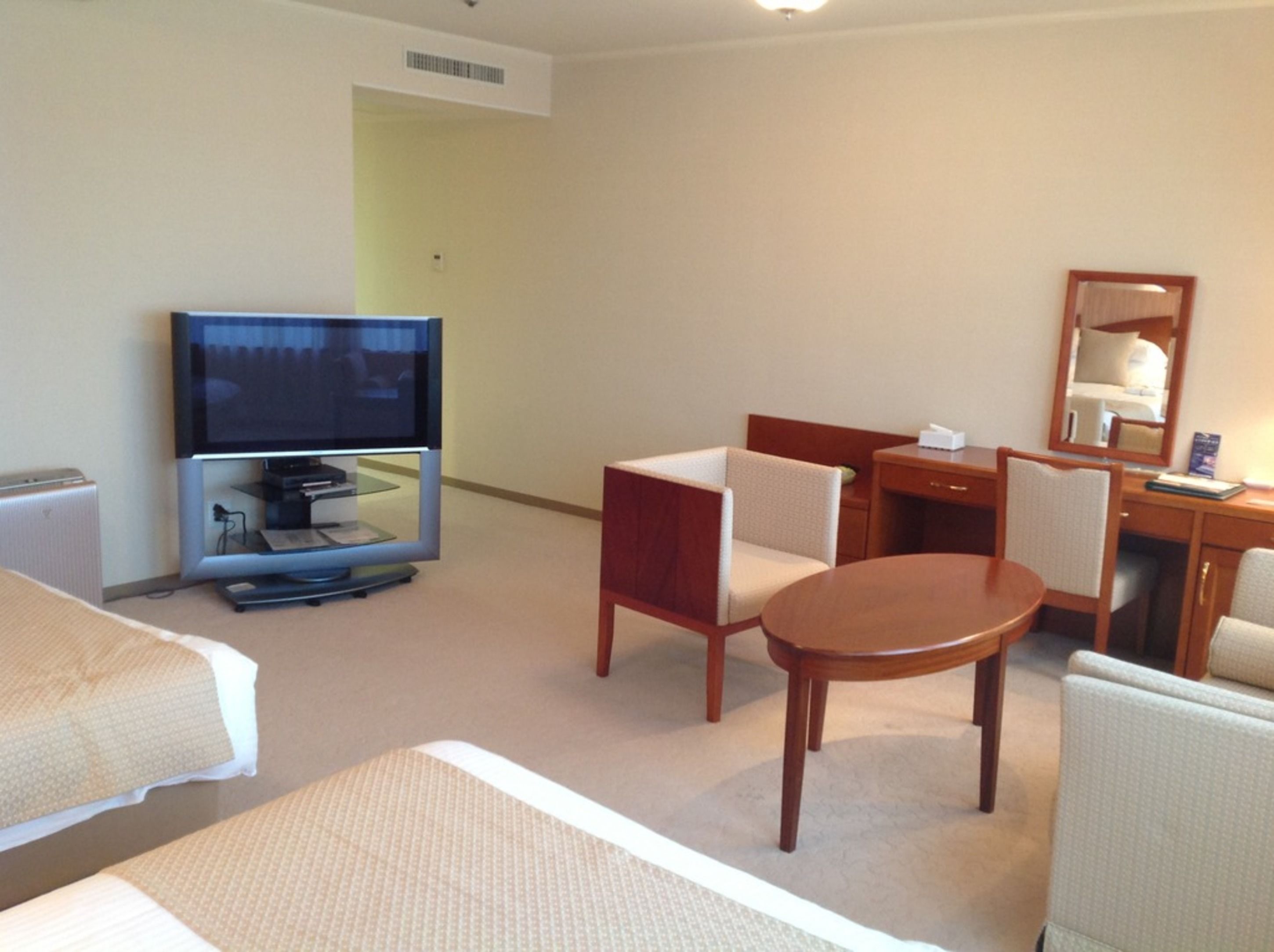 A hotel room with a bed, a TV, a desk, and a chair.