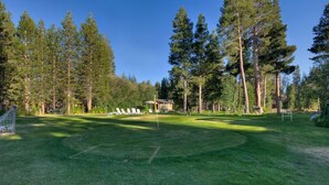 A well-maintained grassy area with a small pavilion, surrounded by tall trees.