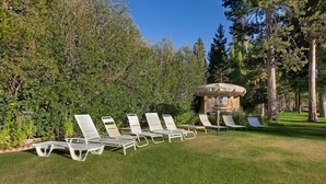 A row of white sun loungers on a grassy lawn with a stone structure in the background.
