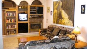 A living room with a sofa, a television, a bookshelf, and a painting on the wall.