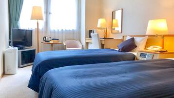 A hotel room with two beds, a desk with a computer, a television, and a telephone.