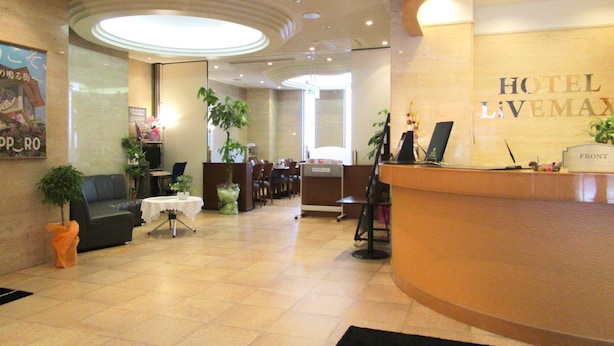 A hotel lobby with a reception desk, seating area, and a large poster on the wall. - HOTEL LiVEMAX Sapporo-Ekimae (Sapporo)