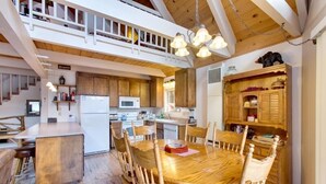 Una cocina amplia con armarios de madera, una isla central y un comedor con una mesa redonda y sillas.