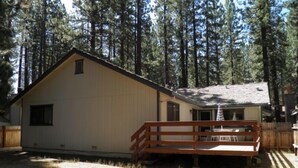 A single-story building with a gabled roof, a small porch with a wooden railing, and a fenced yard. - 1421 Meadow Crest Drive (South Lake Tahoe)