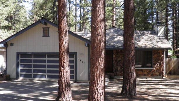 A two-story house with a garage, surrounded by tall trees. - 1421 Meadow Crest Drive (South Lake Tahoe)