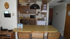 A compact kitchen with a central island, wooden cabinets, a microwave, and a stove. - 1470 Murietta Drive (South Lake Tahoe)