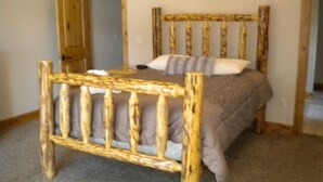 Una cama individual con estructura de madera y colchón gris en una habitación con piso alfombrado y puerta de madera.