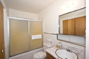 A bathroom with a shower enclosure, toilet, sink, and mirror. - 1823 Hunkpapa St. (South Lake Tahoe)