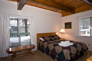 A bedroom with two beds, a bench, a lamp, and a window with curtains. - 1823 Hunkpapa St. (South Lake Tahoe)