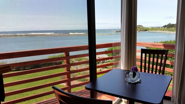 A balcony with a table and chairs, overlooking a beach and ocean. - Arky's B&B (Smith River)