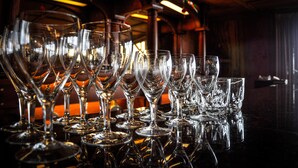 A bar area with numerous empty wine glasses and bottles, reflecting on the polished surface. - Arky's B&B (Smith River)
