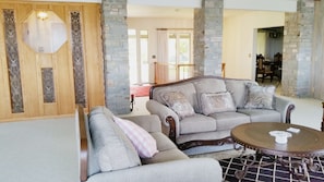 A spacious living room with a grey sofa set, a round coffee table, and a stone accent wall. - Arky's B&B (Smith River)