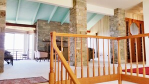 A spacious interior with a wooden staircase, stone pillars, and a high ceiling with blue beams. - Arky's B&B (Smith River)